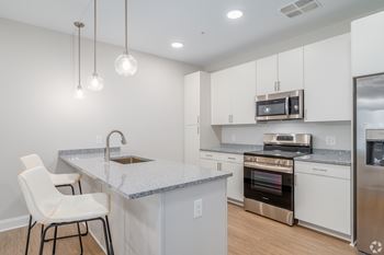 A kitchen with white cabinets and a granite countertop. at Park Lamont Townhomes Apartments, Cleveland